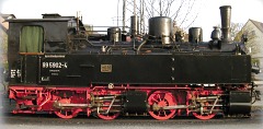 Foto: vierachsige Mallet–Lokomotive mit schwarzem Aufbau und rotem Fahrwerk.