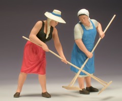 Zwei Frauen bei der Heuernte, eine junge mit Hut und eine ältere mit Kopftuch.