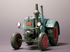 Graublaues Traktormodell mit Frontbeleuchtung im Halbdunkel.