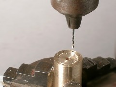 In die Stirnseite eines Zylinders werden rundum am Rand kleine Löcher gebohrt.