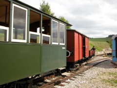 Schmalspur–Personenwagen und Güterwagen im Bahnhof.