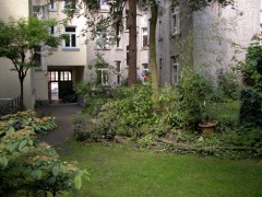 Blick durch einen Garten zu einem Hof mit anschließendem Torweg.