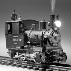 Schwarzweißes Modellfoto: Kleine, zweiachsige Dampflok schräg von vorne.
