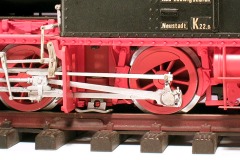 Detailfoto: Fahrwerk einer zweiachsigen Lokomotive mit einem Schienenschleifer zwischen den Rädern.