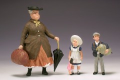Drei Figuren: eine extrem dicke Frau mit Hut, Tasche und Schirm und zwei Kinder.