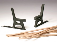 Zwei schwarze Kunststoff–Beinteile und einige Holzleistchen für eine Sitzbank.