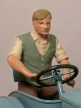 Die Figur eines Mannes mit grüner Weste und Seitenscheitel lenkt einen Traktor.