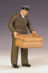 Eine umgebaute Figur trägt eine leere Holzkiste.