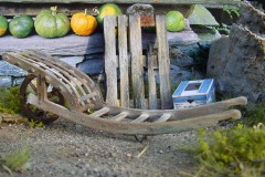 Modellfoto: alte Gartenkarre mit rostigen Beschlägen und Zuckerrüben darin zwischen zwei Feldbahngleisen.