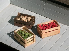 Modellfoto: Drei verschiedene Holzkisten mit Obst und Gemüse auf einem Waggon.