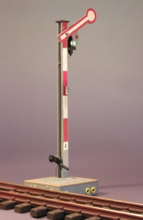 Modellfoto: Umgebautes Formsignal mit rot–weißem Flügel und grünem Licht.