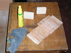 Sperrholz–Streifen mit vielen quer aufgeklebten Eisstäbchen aus Holz.
