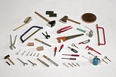 Modellfoto: viele verschiedene Werkzeuge, rechts hinten zum Größenvergleich ein 1 Cent–Stück.