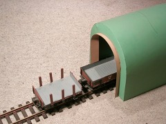 Foto: aus Karton gebastelter, grüner Tunnel über einem Gleis mit kurzen Wägelchen.