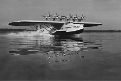 Zwölfmotoriges Flugboot beim Start auf dem Wasser.
