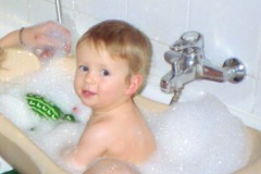 Foto: Ein Baby plantscht in einer Kinderbadewanne.