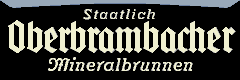Emaille–Schild mit dreizeiligem Schriftzug „Staatlich Oberbrambacher Mineralbrunnen” (elfenbein auf schwarz).
