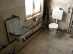 Blick auf Waschbecken und Toilette in einem noch unrestaurierten Raum.