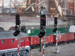 Eine rote Diesellok (BR 132) hält vor einem Lichtsignal.