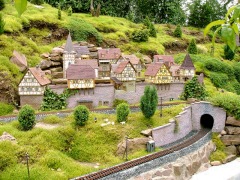 Eine Stadt aus Fachwerkhäusern auf einer Gartenbahn, davor zwei Gleise.