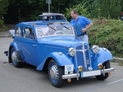 Foto: Mittelblaue Cabrio–Limousine mit geöffnetem Dach, schräg von vorne.