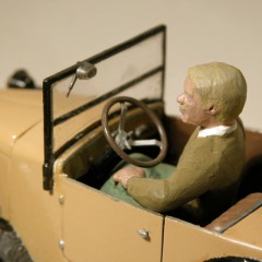 Modellfoto: Blonder Mann mit Walroß–Schnauzbart im offenen Kleinwagen.