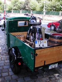 Auf der Tiefpritsche des Goliath stehen ein Motorrad und ein Bierfass aus Holz.