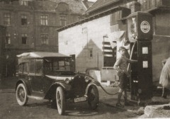 Klein–Limousine an Tankstelle, ein Junge steht an der Zapfsäule.