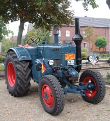 Blauer Traktor mit roten Felgen und Kotflügeln hinten, offener Führerstand.