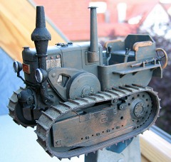 Modellfoto: hell graublauer Traktor mit Raupenketten am offenen Fenster.