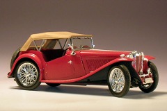 Modellfoto: roter Roadster mit geschlossenem, beigefarbenen Dach von der Seite.