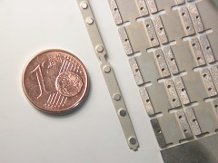 Aus Neusilber geätzte Schienenplatten und Schienenlaschen, eine 1 Cent-Münze.
