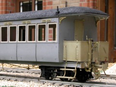 Ein unlackiertes Reisezugwagen–Modell aus Metall, schräg von der Seite.
