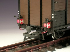 Modellfoto: Beleuchtete Zugschluss–Laternen an einem gedeckten Güterwagen.