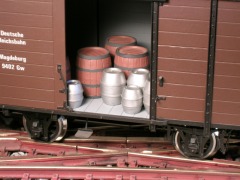 Modellfoto: Blick durch die offene Schiebetür in den Laderaum eines Wagens, innen Fässer aus Holz und Aluminium.