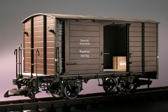 Modellfoto: Gedeckter Güterwagen mit offenen Schiebetüren, innen eine Kiste.