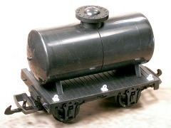 Modellfoto: kleiner, schwarzer Güterwagen mit einem Kessel auf zwei Stützen.