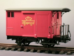 Gedeckter Güterwagen mit rotem Bretteraufbau und einer überdachten Bremserbühne.