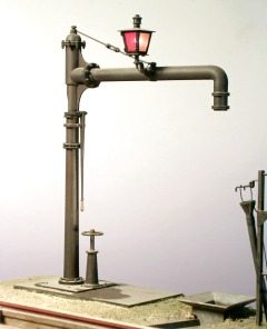 Modellfoto: kleiner Wasserkran aus Messing mit beleuchteter Warnlaterne.