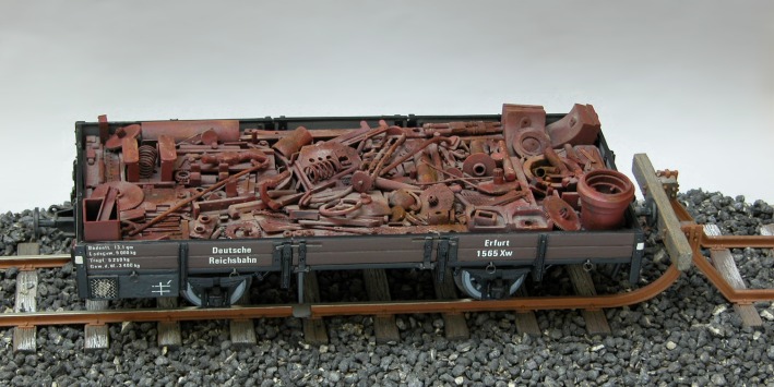 Ein Niederbordwagen mit Schrottladung.