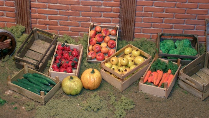 Mehrere Kisten mit Obst und Gemüse vor einer Backsteinwand.