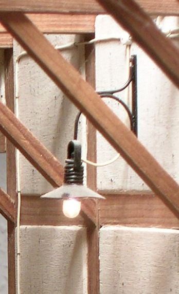 An einem Ausleger befestigte Wandlampe in einem Fachwerkgebäude.