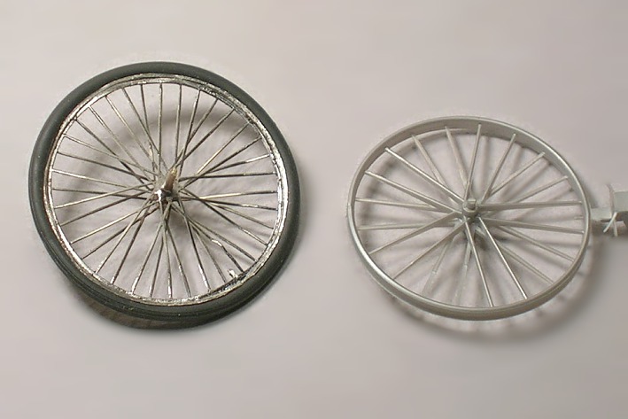 Ein Modellfahrrad–Rad mit dünnen Metallspeichen und ein Kunststoffrad mit wenigen, dicken Speichen.