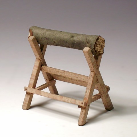 Modell: ein hölzerner Sägebock mit gekreuzten Beinen, darauf ein Holzstück.