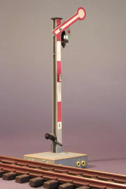 Modellfoto: Umgebautes Formsignal mit rot–weißem Flügel und grünem Licht.