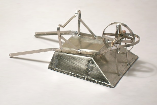Modell–Schubkarre aus Metall, überkopf. Das Rad hat eine flache Blechfelge.