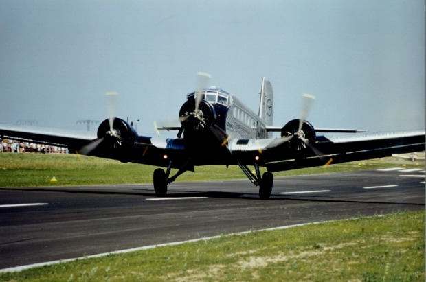 Dreimotoriges Flugzeug beim Start auf Rollbahn, von schräg vorne.