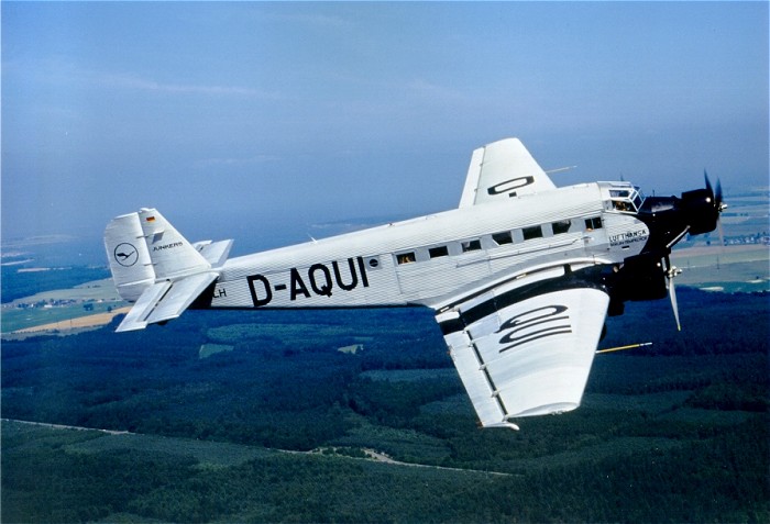 Ju 52 von der Seite im Flug über einem Waldstück.