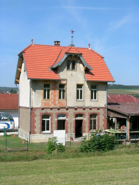 Zweigeschossiges Bahnhofsgebäude mit einem Ladeboden und Güterschuppen.