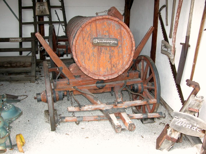 Ein Jauchewagen aus Holz und andere landwirtschaftliche Geräte (um 1930).